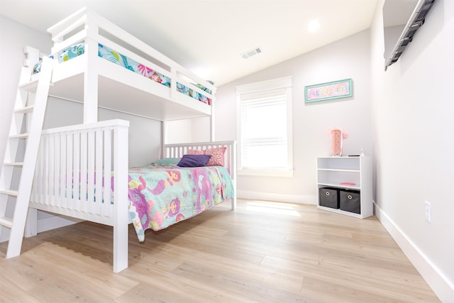 bedroom featuring baseboards, vaulted ceiling, visible vents, and wood finished floors