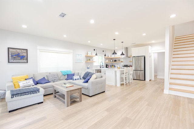 living room featuring recessed lighting, stairs, visible vents, and light wood-style floors