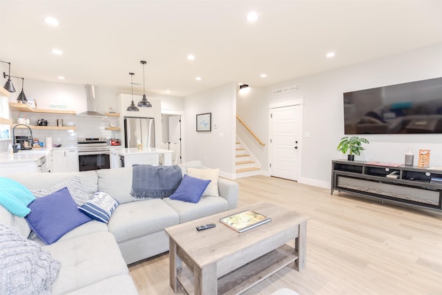living area featuring baseboards, stairs, light wood-style flooring, and recessed lighting