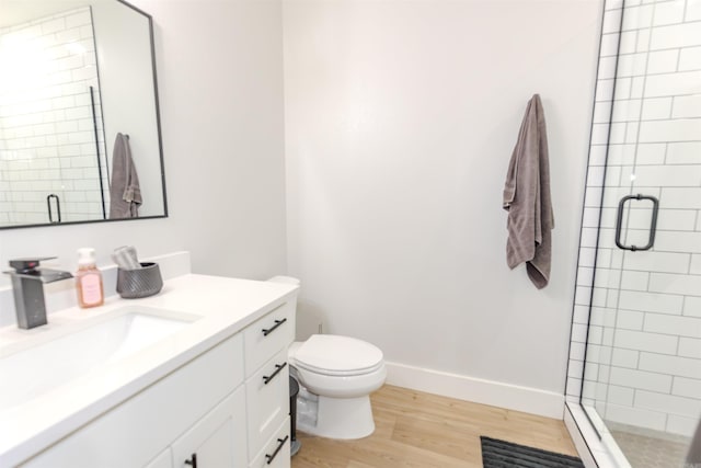 bathroom featuring a shower stall, baseboards, wood finished floors, toilet, and vanity