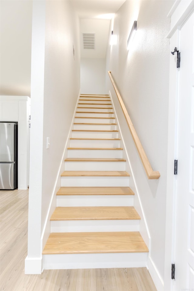 staircase with wood finished floors and visible vents