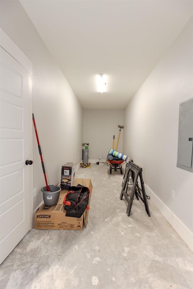 interior space featuring electric panel, baseboards, and unfinished concrete flooring