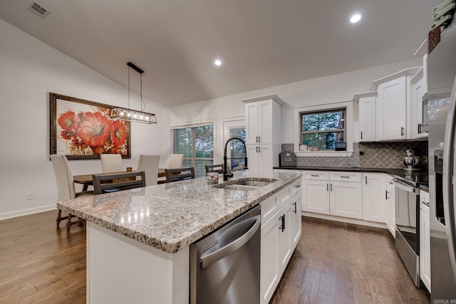kitchen featuring vaulted ceiling, stainless steel appliances, decorative backsplash, a sink, and visible vents