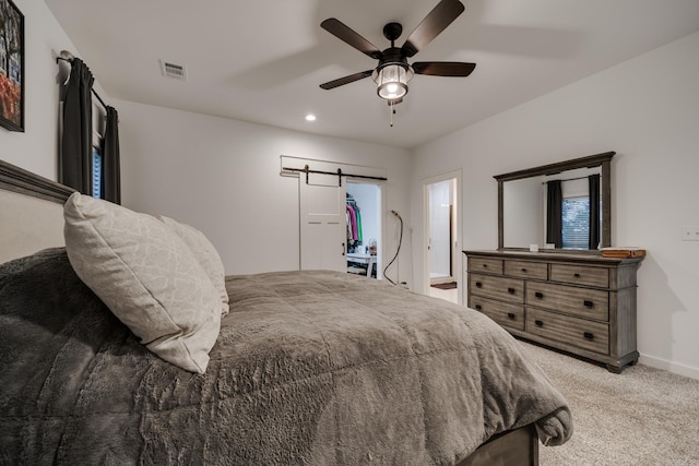 bedroom with light carpet, a barn door, baseboards, visible vents, and ceiling fan