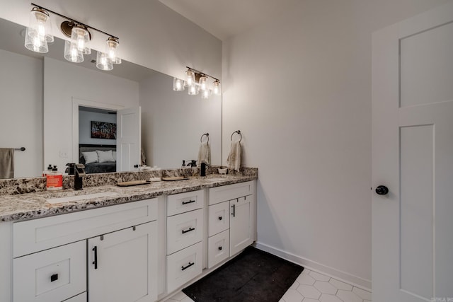 bathroom featuring double vanity, a sink, baseboards, and ensuite bath