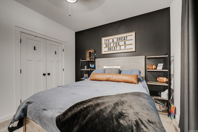 bedroom featuring carpet, baseboards, an accent wall, ceiling fan, and a closet