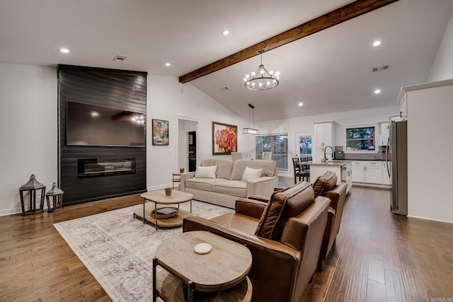 living area featuring dark wood-style flooring, visible vents, a chandelier, and beamed ceiling