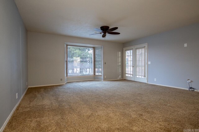 carpeted empty room featuring baseboards, ceiling fan, and a wealth of natural light