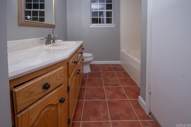 bathroom featuring toilet, vanity, tile patterned flooring, a bath, and baseboards