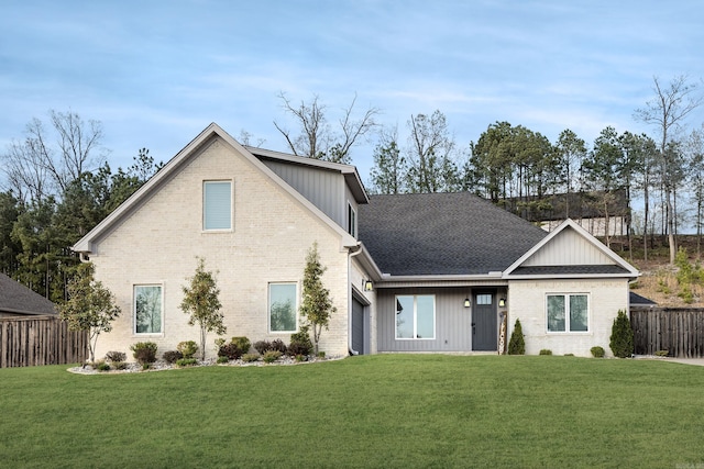view of front of property with a shingled roof, a front yard, fence, and brick siding