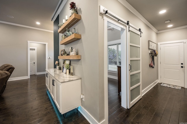 hallway with baseboards, a barn door, ornamental molding, and dark wood-style flooring