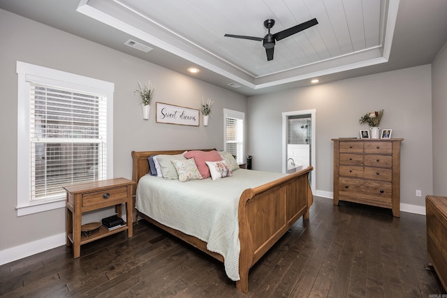 bedroom featuring dark wood-style flooring, visible vents, baseboards, ceiling fan, and a raised ceiling