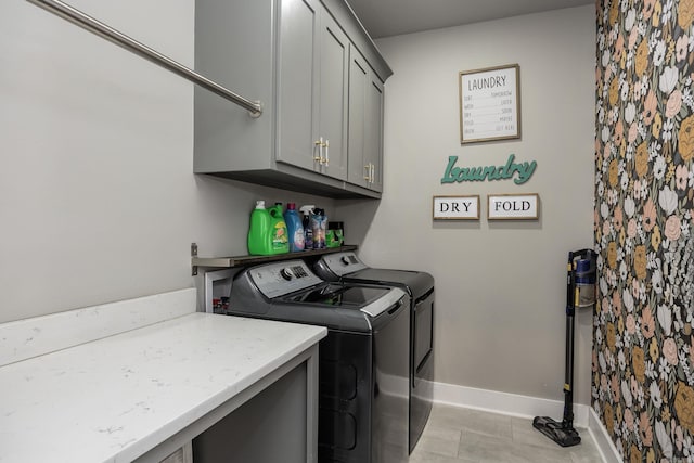 washroom featuring baseboards, cabinet space, and independent washer and dryer