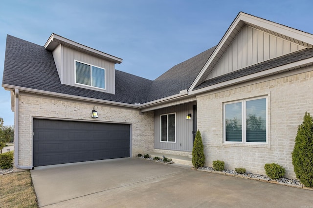 view of front facade featuring an attached garage, brick siding, board and batten siding, driveway, and a shingled roof