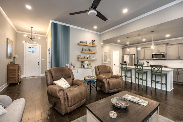 living room with crown molding, recessed lighting, ceiling fan with notable chandelier, dark wood-type flooring, and baseboards