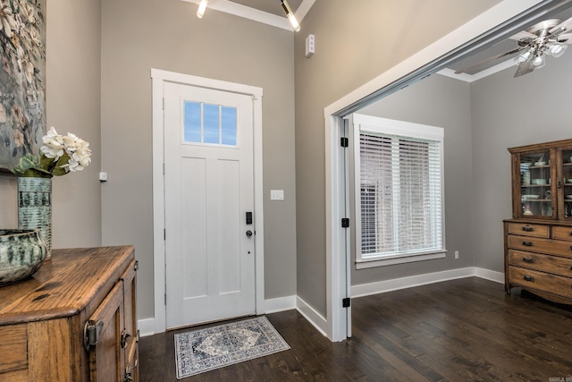 foyer entrance with a ceiling fan, ornamental molding, dark wood-style floors, and baseboards
