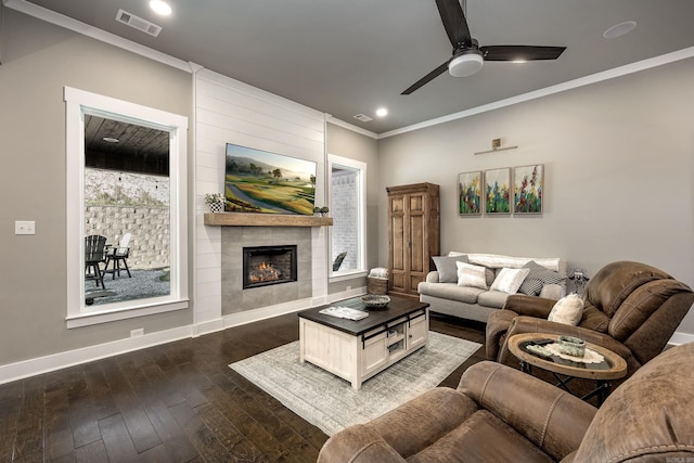 living area featuring a ceiling fan, dark wood-type flooring, baseboards, visible vents, and ornamental molding