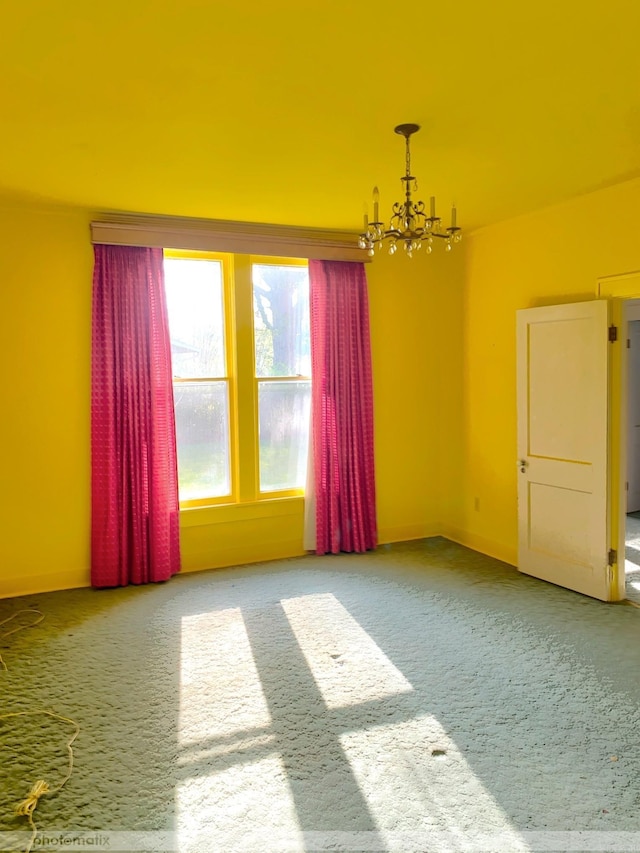 unfurnished room with baseboards, a chandelier, and carpet