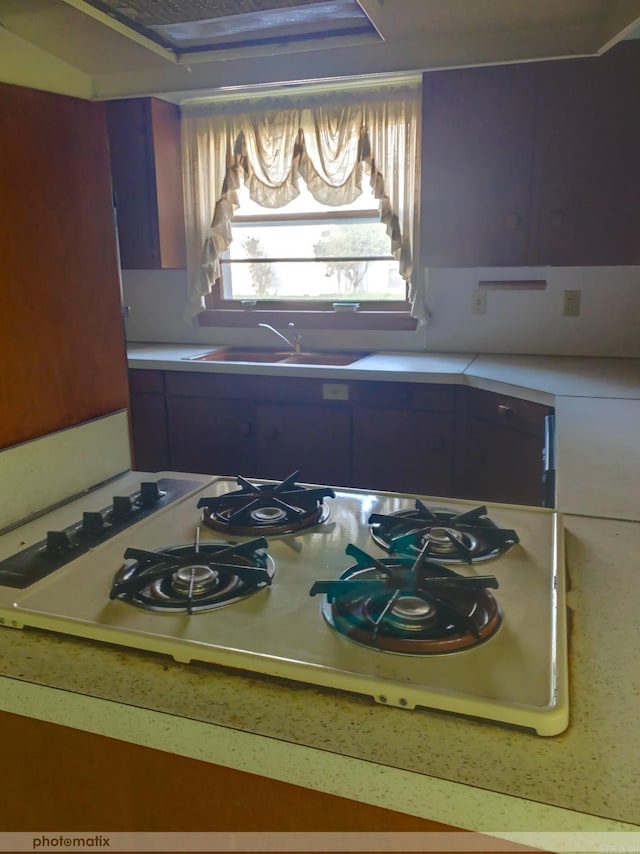 kitchen featuring light countertops, a sink, and white gas cooktop