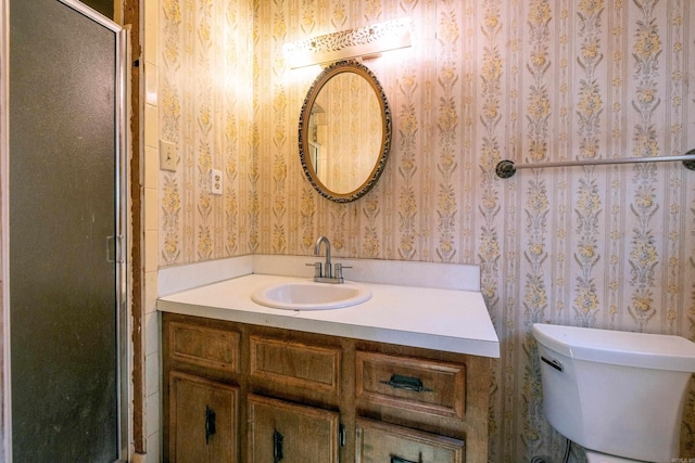 full bathroom with toilet, wallpapered walls, vanity, and a stall shower