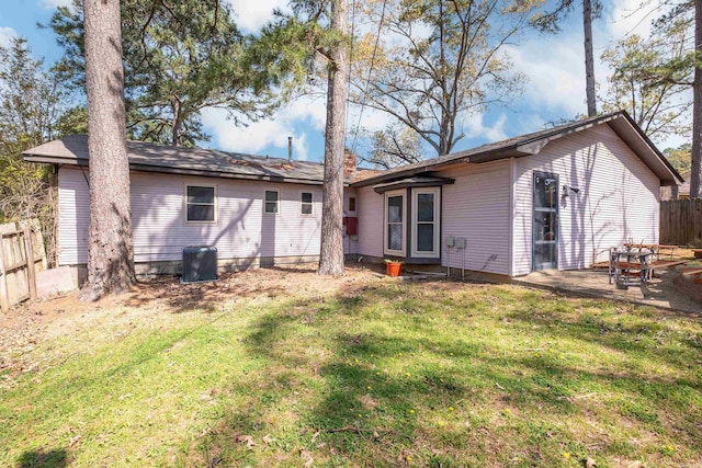 rear view of property featuring cooling unit, fence, and a lawn
