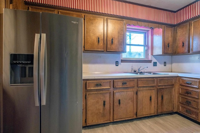 kitchen with brown cabinetry, light countertops, stainless steel refrigerator with ice dispenser, and light wood-style floors