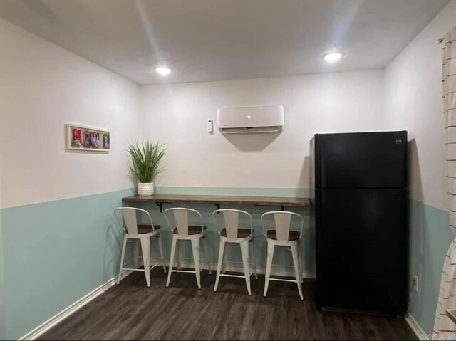 6 Timber Ridge Dr, Atlanta, TX 75551 - kitchen with freestanding refrigerator, a wall unit AC, wood finished floors, a kitchen bar, and baseboards