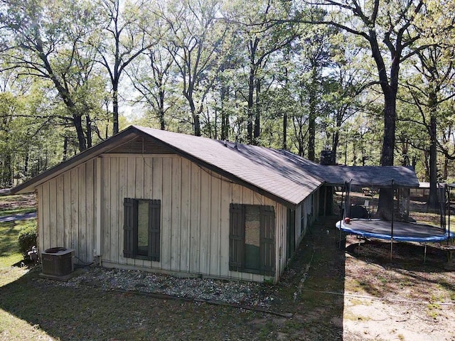 view of outbuilding with a carport, a trampoline, and central AC unit