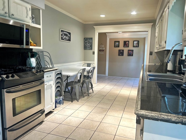 kitchen featuring light tile patterned flooring, a sink, ornamental molding, and stainless steel appliances
