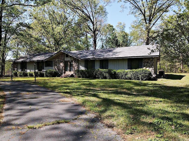 view of front of property featuring aphalt driveway, a front yard, and stone siding