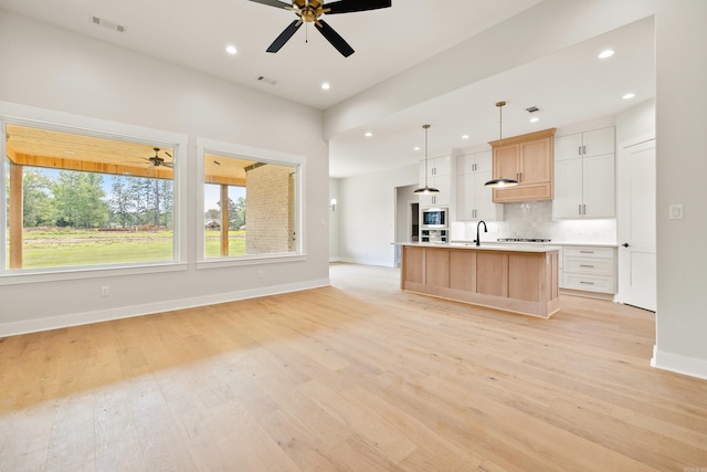 6172 Majestic Waters Dr, Alexander, AR 72002 - kitchen featuring ceiling fan, backsplash, light wood finished floors, baseboards, and a kitchen island with sink