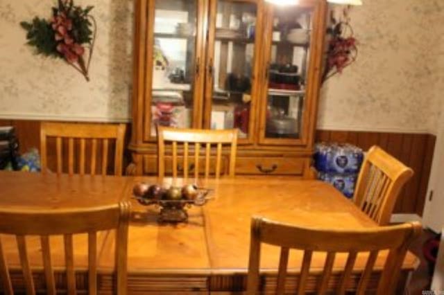 dining space featuring a wainscoted wall and wallpapered walls