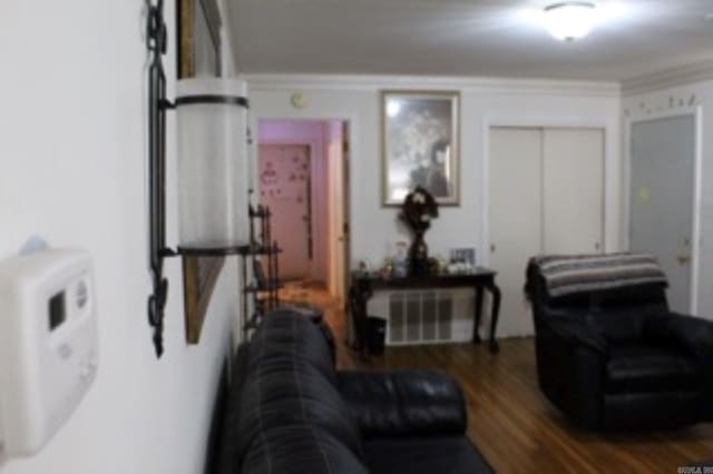 living area with crown molding and wood finished floors