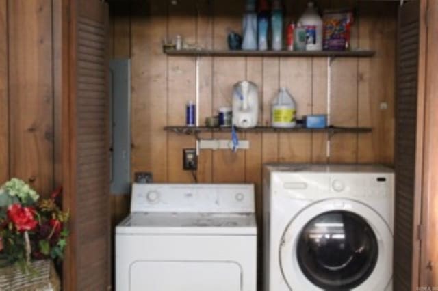 washroom with independent washer and dryer, wood walls, and laundry area