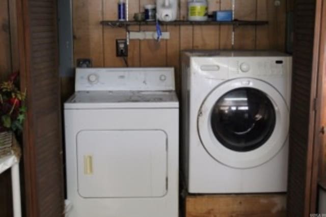 laundry room featuring independent washer and dryer, wood walls, and laundry area