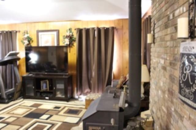 living room featuring a wood stove and brick wall