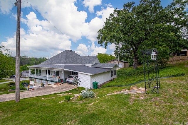 view of side of home featuring driveway, a carport, a lawn, a shingled roof, and a porch