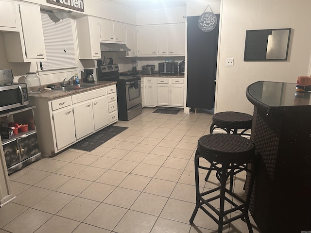 400 Oxford St, West Memphis, AR 72301 - kitchen with light tile patterned floors, white cabinets, under cabinet range hood, stainless steel appliances, and a sink