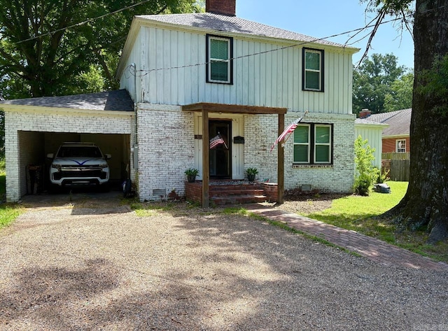 view of front of home featuring brick siding, a chimney, driveway, and board and batten siding
