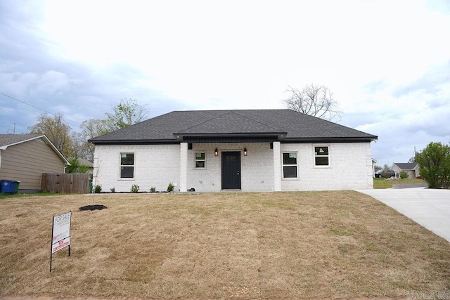 view of front of house featuring a front yard, fence, brick siding, and roof with shingles
