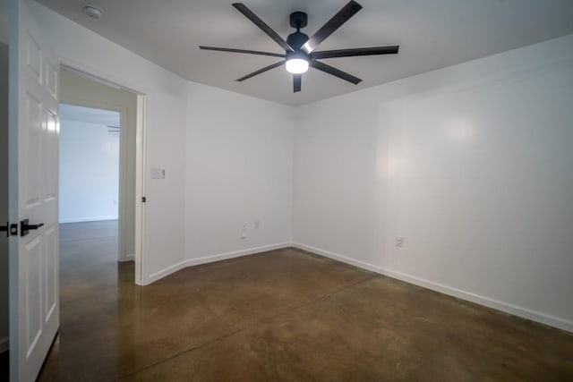 empty room with ceiling fan, finished concrete floors, and baseboards