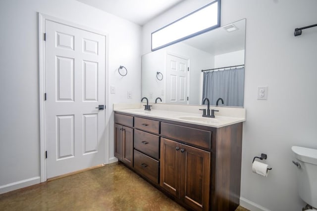 full bath featuring double vanity, concrete floors, a sink, and toilet
