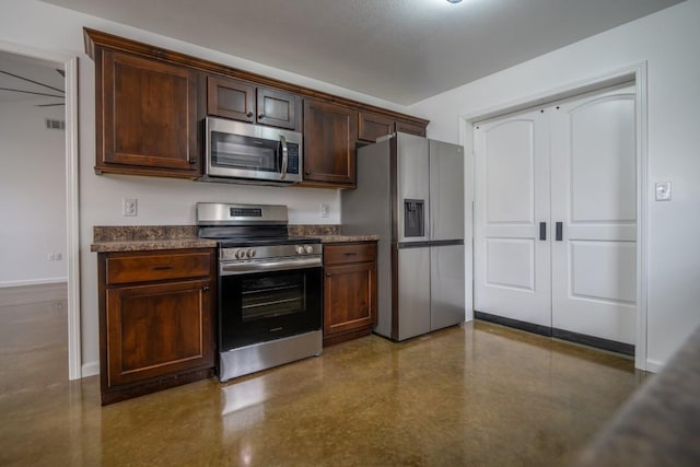 kitchen with stainless steel appliances, dark brown cabinetry, baseboards, and dark countertops