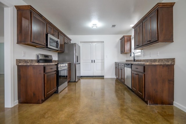 kitchen featuring dark countertops, dark brown cabinetry, baseboards, and appliances with stainless steel finishes