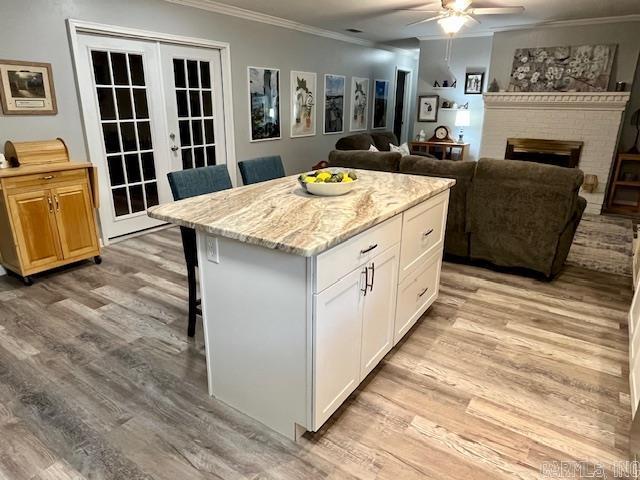 208 Pine Forest Ln, Fordyce, AR 71742 - kitchen with ornamental molding, a ceiling fan, french doors, a kitchen breakfast bar, and light wood-style flooring