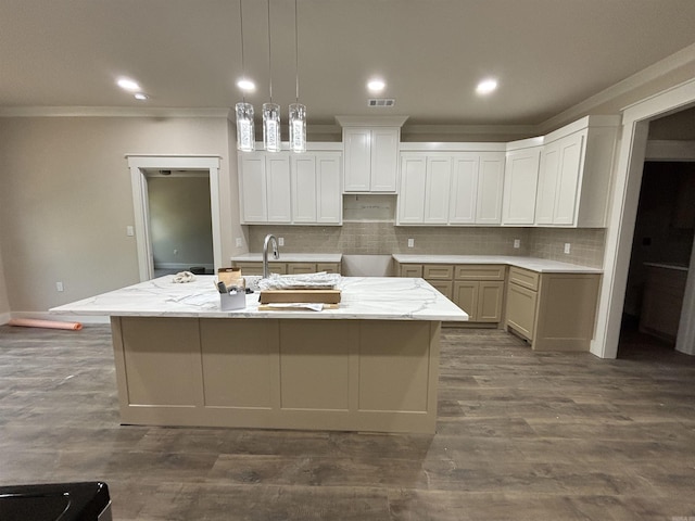 228 Michelle Dr, Beebe, AR 72012 - kitchen with crown molding, tasteful backsplash, a kitchen island with sink, decorative light fixtures, and dark wood-style flooring