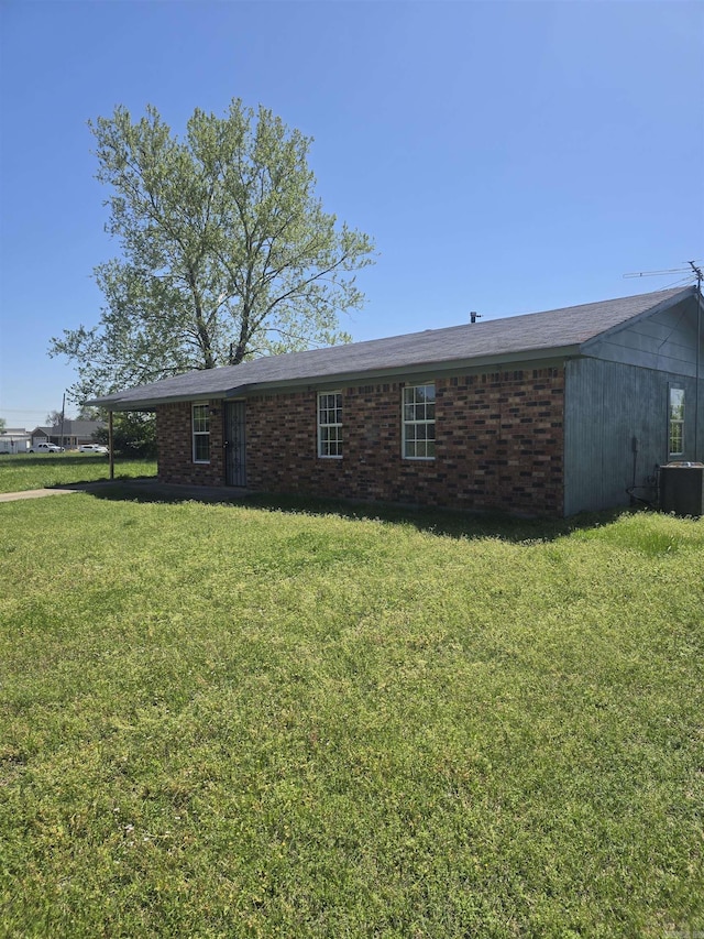 exterior space featuring a front yard, central AC unit, and brick siding