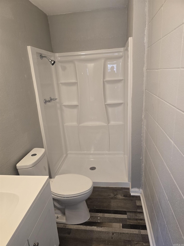 full bathroom featuring a shower stall, vanity, toilet, and wood finished floors