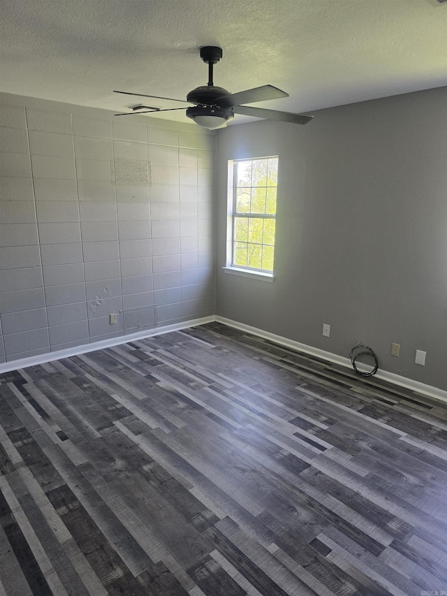 spare room with a textured ceiling, a ceiling fan, and dark wood finished floors