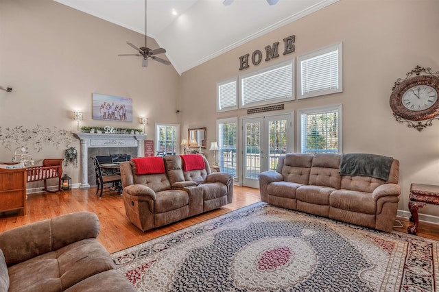 living area featuring light wood finished floors, high vaulted ceiling, a ceiling fan, and a fireplace